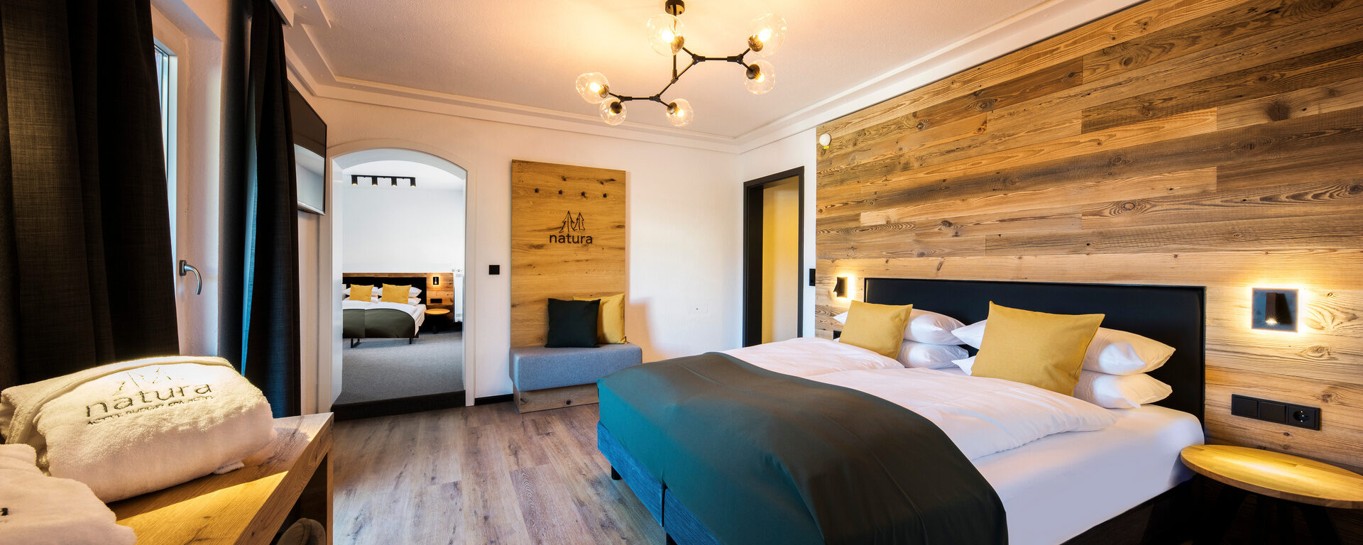 Ein gemütliches Schlafzimmer mit Holzwänden und einladender Einrichtung in der Bodenmais Junior Suite im natura Hotel im Bayerischen Wald.