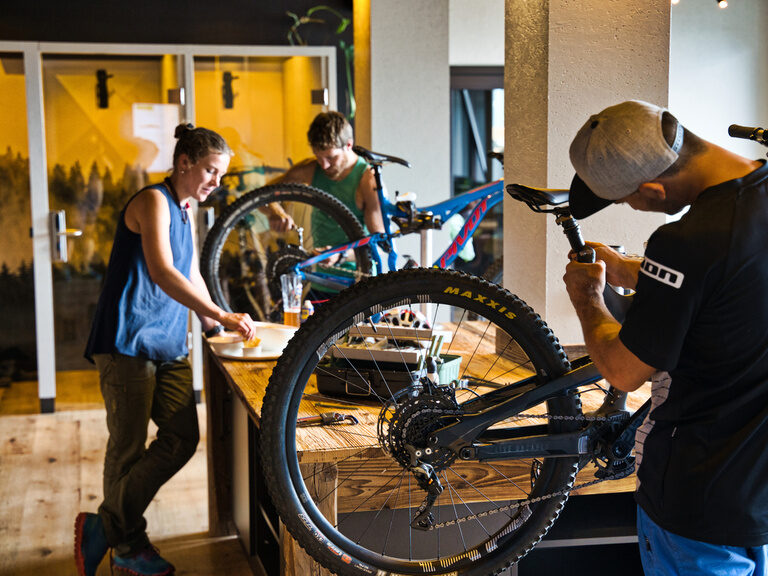Ein Mann arbeitet an einem Reifen eines Mountainbikes in der natura Sport Lounge im Bayerischen Wald.