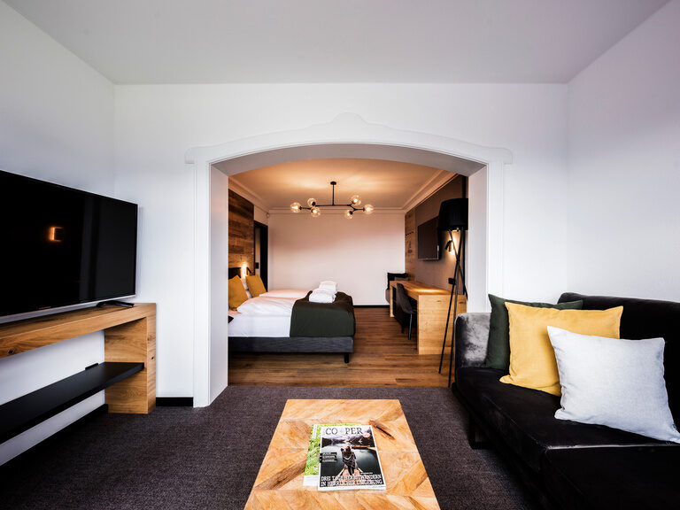 Geschmackvoll eingerichteter Wohnbereich mit Couch und TV im natura Bodenmais Superior Hotelzimmer