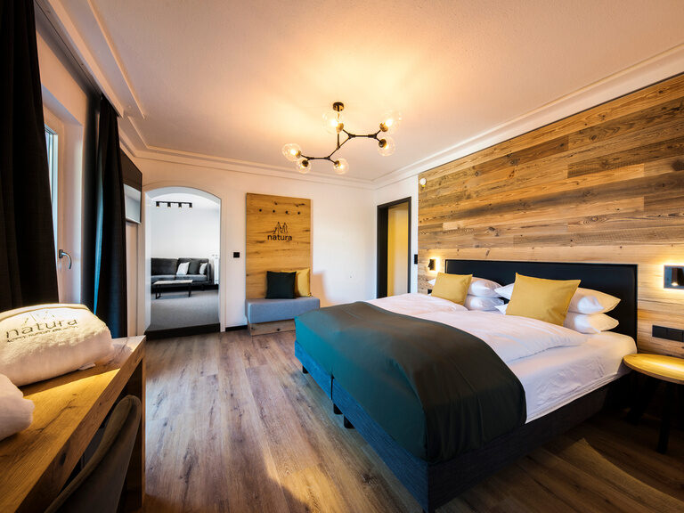 Einladendes Schlafzimmer der Junior-Suite voller natürlicher Möbel im Wellness-Resort natura.