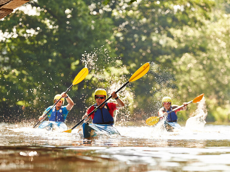 Eine Gruppe von Kanufahrern paddelt auf einem Fluss in der nähe von Bodenmais