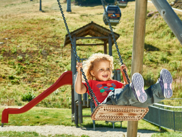 Ein Kind hat großen Spaß beim schaukeln auf einem Spielplatz in der Nähe des Bayerischen Waldes.