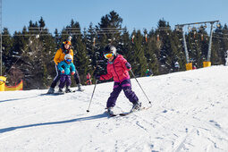 Eine Gruppe von Kindern lernt auf einem Übungshang in Bodenmais das Skifahren.