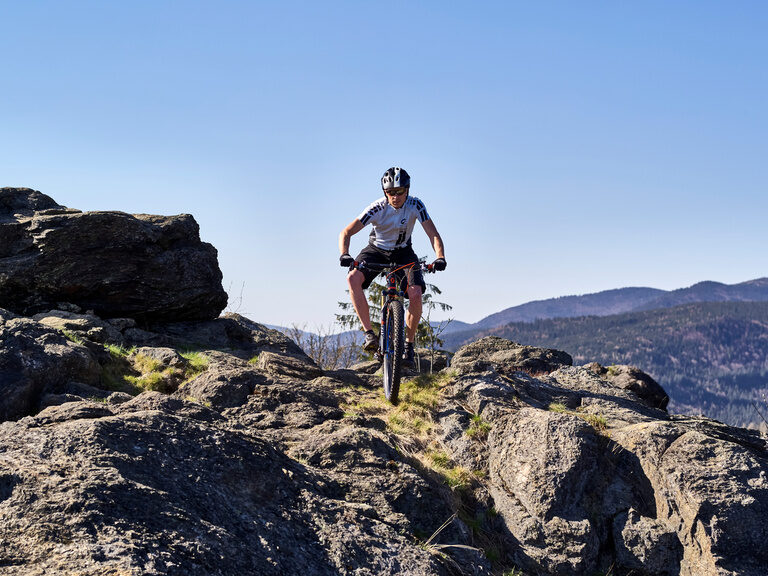 Ein Mountainbiker ist mit seinem Bike auf steinigem Terrain im Bayerischen Wald unterwegs