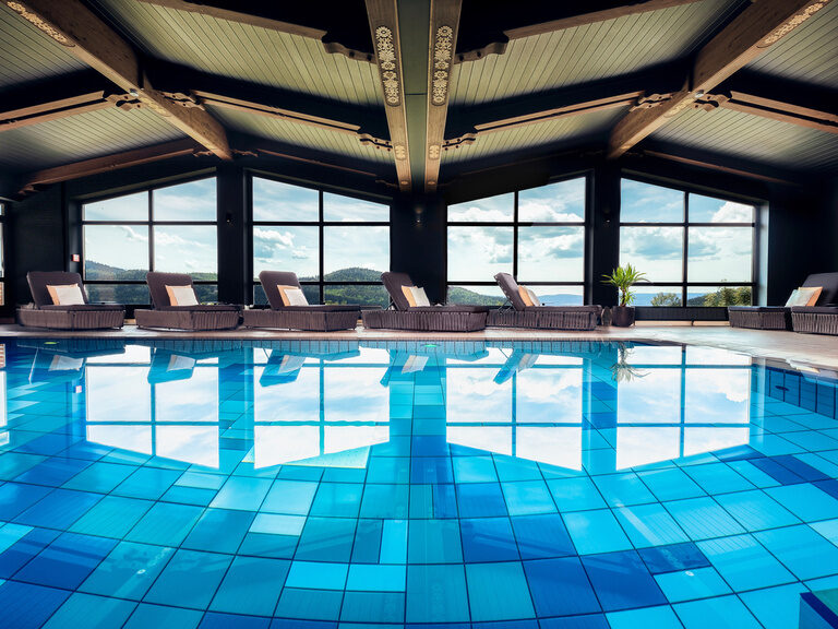 Das Panorama-Hallenbad im Wellnessbereich des natura Hotel Bodenmais mit Blick auf Bayerischen Wald.