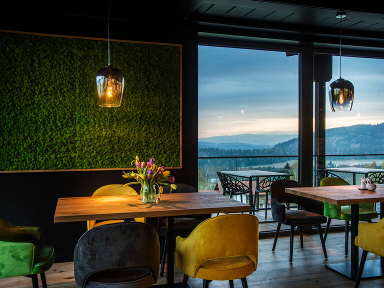 Stilvoll eingerichtetes Restaurantzimmer mit Tisch und Blick auf den Bayerwald