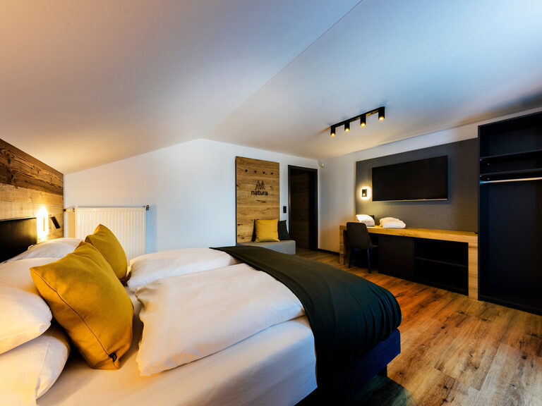 Ein gemütliches Schlafzimmer mit einem komfortablen Bett und Fernseher im Bodenmais Family & Friends Zimmer.