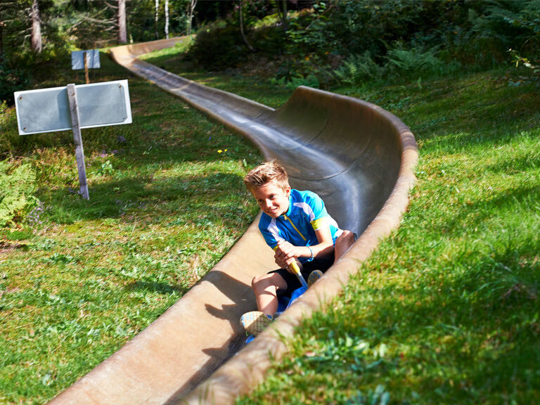 Ein Kind erlebt aufregenden Spaß auf der Sommerrodelbahn bei der Silberbergbahn Freizeitanlagen.