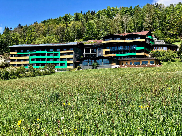 Das natura Hotel Bodenmais im Bayerischen Wald mit blühender grüner Wiese im Vordergrund an einem schönen Sommertag