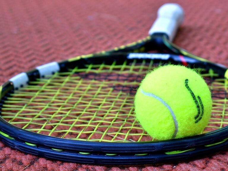 Ein Tennisschläger liegt mit einem Tennisball auf dem Tennisplatz nahe dem natura Hotel Bodenmais