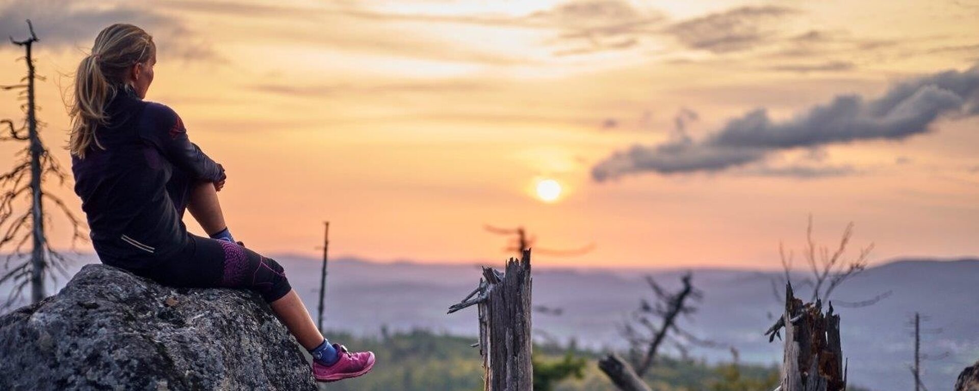 Eine Wanderin genießt bei Sonnenuntergang die Ruhe der Wildnis im Bayerischen Wald.
