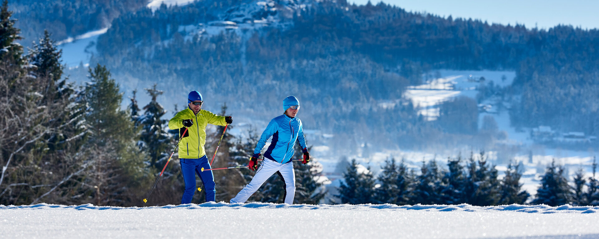 Zwei Langläufer beim Wintersport mit Silberberg im Hintergrund.